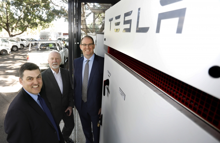 Three men in front of Tesla machine